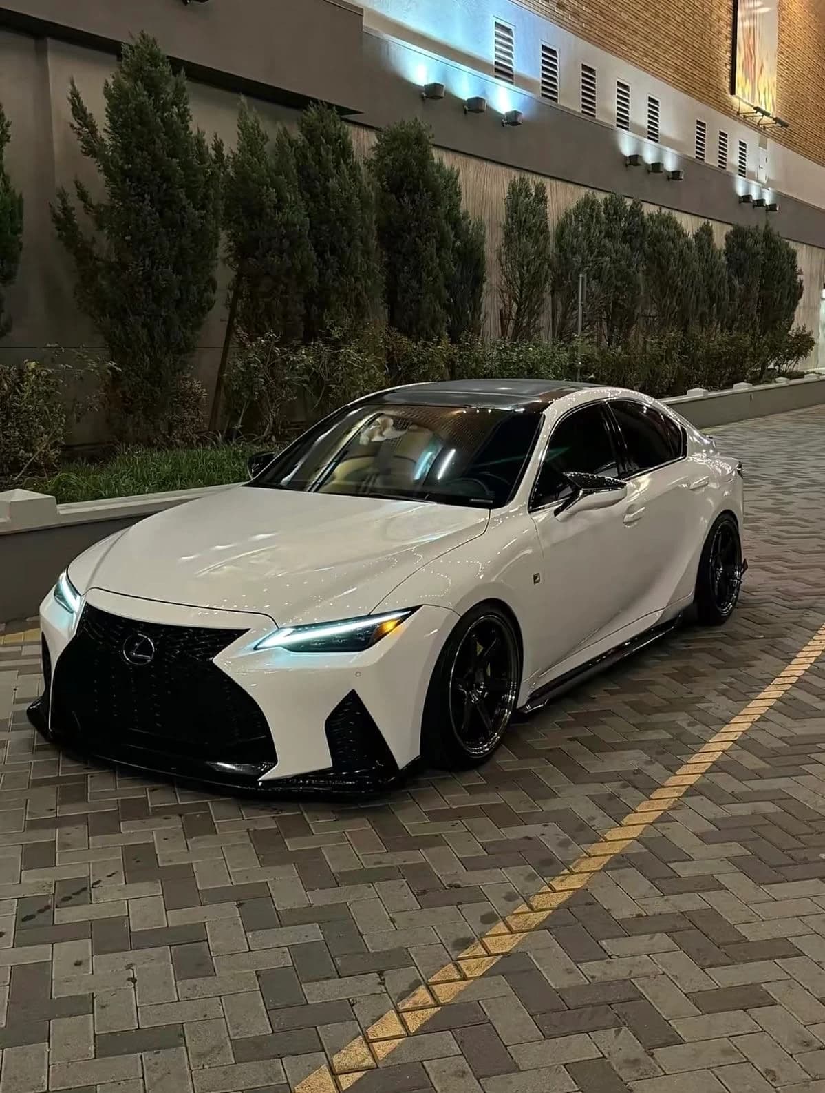 Nighttime phone photo of a white modified Lexus